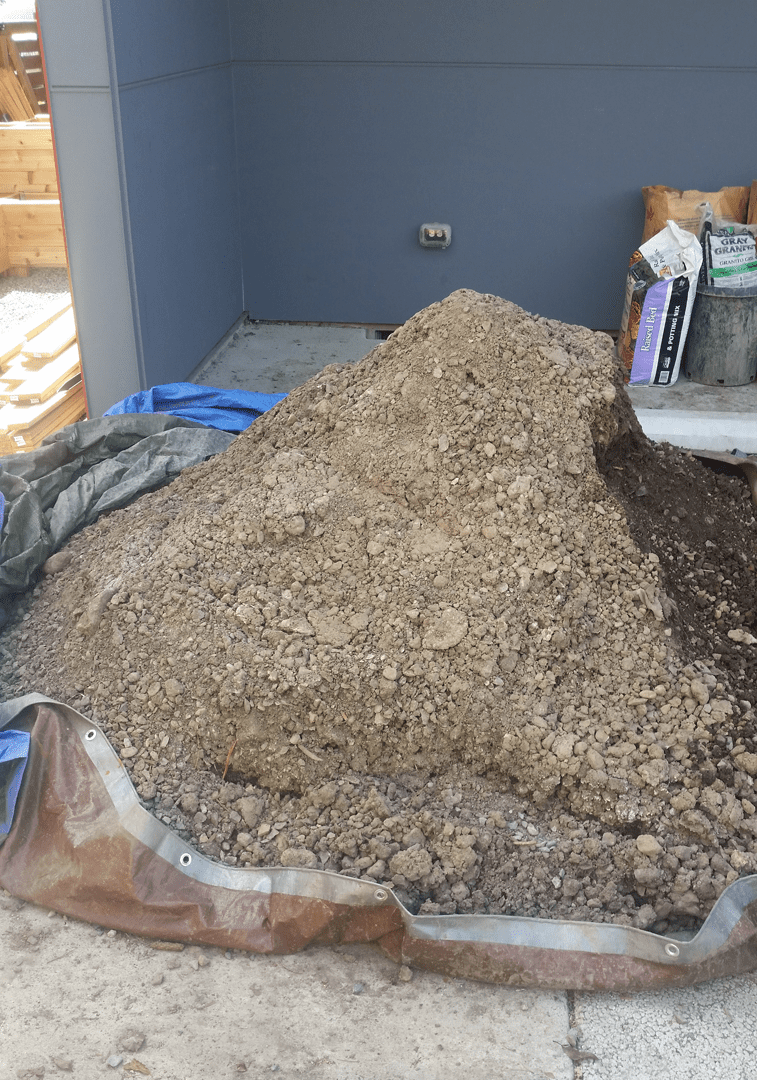 Dirt pile on a construction site with surrounding tarps and debris, illustrating bulk dirt removal services by Seattle Rubbish Removal.