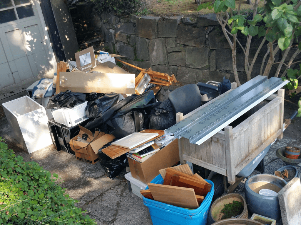 Cluttered driveway filled with assorted junk, including furniture, boxes, and bags, highlighting the need for Seattle Rubbish Removal services for efficient junk removal in Bellevue.