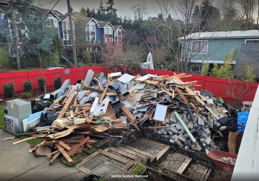 Piled junk debris including wood, metal, and construction materials in a residential yard, highlighting the need for efficient junk removal services by Seattle Rubbish Removal.
